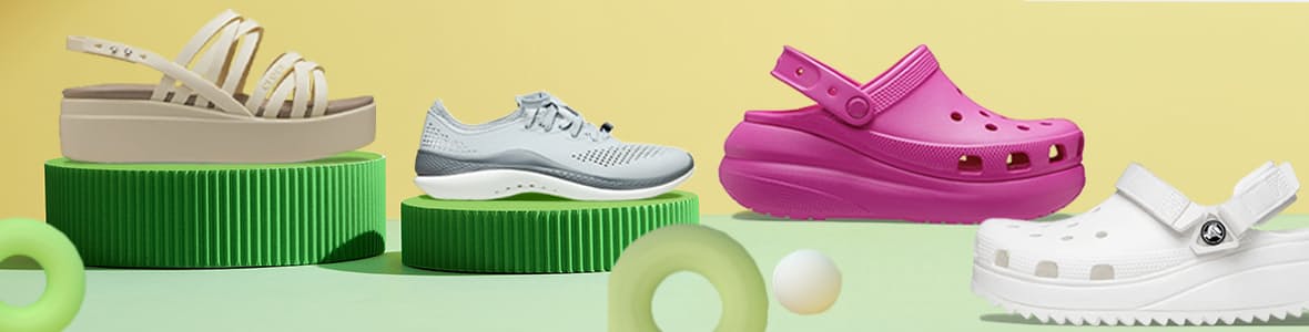 Four pairs of Crocs shoes in various colors, showcasing the iconic lightweight, breathable design with adjustable straps and perforated uppers.