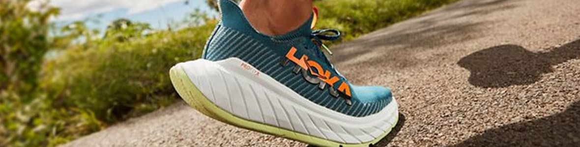 Close-up of a blue, green, and white HOKA shoe in action, showcasing its performance on the move.